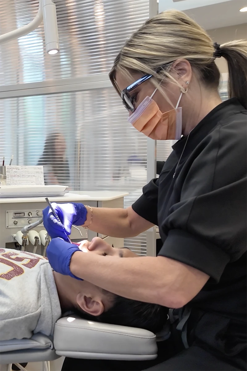 A dental assistant at christensen orthodontics cleaning a kid's teeth A dental assistant at christensen orthodontics cleaning a kid's teeth